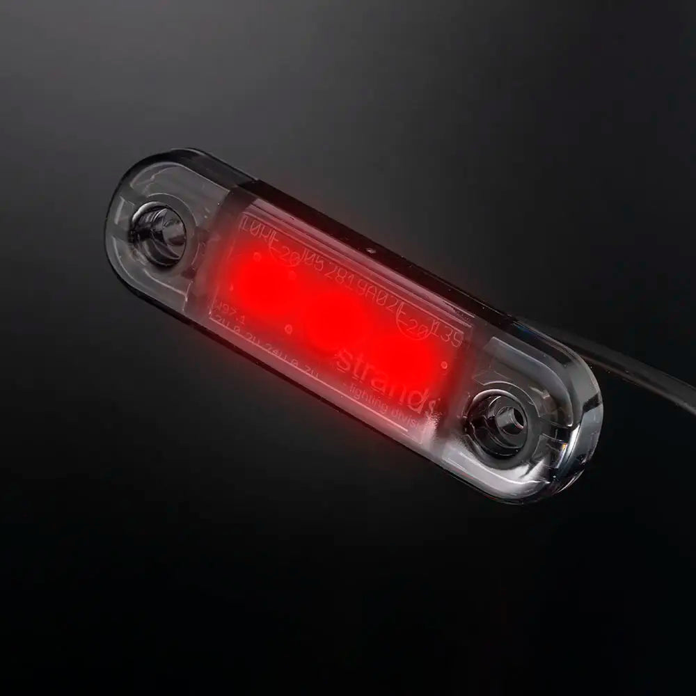 Kapea punaisena loistava LED-äärivalo tummalla linssillä kuvattuna viistosta mustaa taustaa vasten.